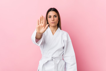 Young karate woman standing with outstretched hand showing stop sign, preventing you.