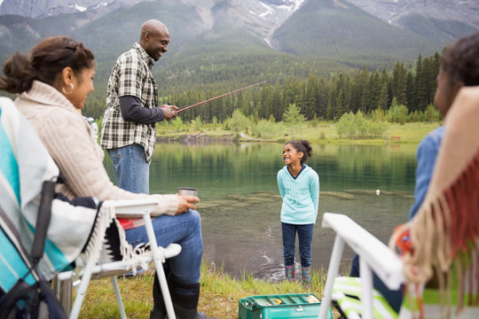 Family fishing at lakeside below mountains