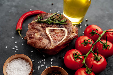 grilled steak, with tomatoes and spices on a stone background.