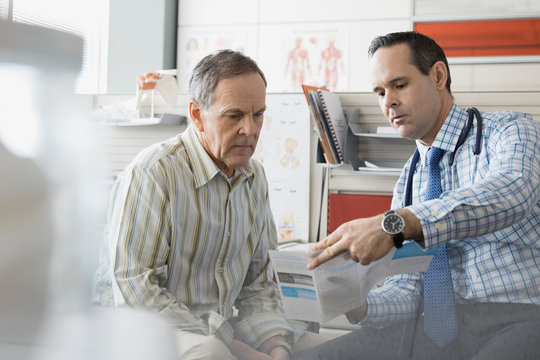 Doctor showing senior patient brochure in office