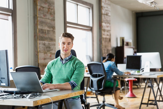 Portrait of entrepreneur sitting at desk in creative office space