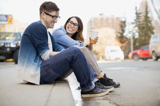 Hipster couple drinking coffee on urban curb