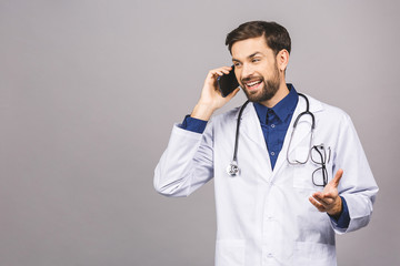 Close up shot of handsome man doctor isolated on grey background talking on smartphone, smiling positively