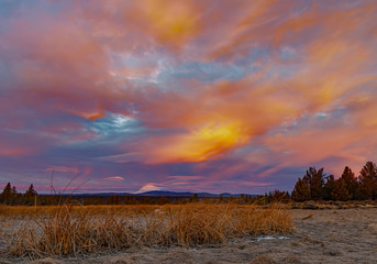 Sunrise from a highdesert winter pond with cloud capped Mt. in the distance