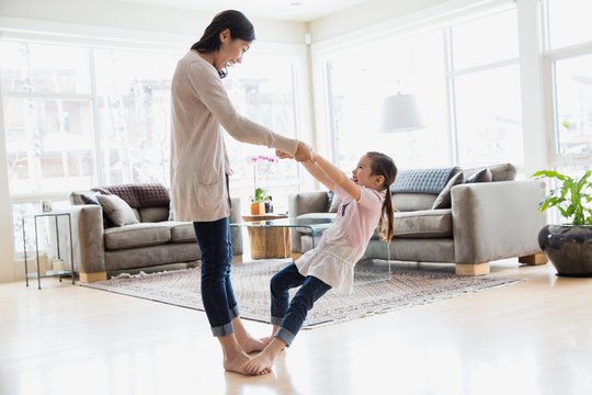 Daughter dancing on mothers feet in living room