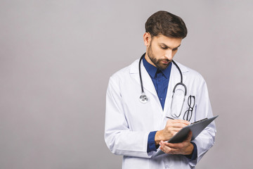 Serious doctor writing recipe on clipboard, isolated on grey background.