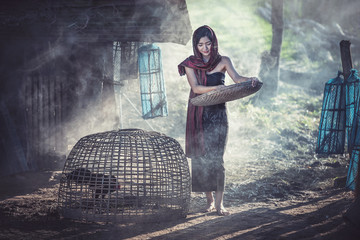 Beautiful girl winnowing rice separate between rice and rice husk, Thailand countryside
