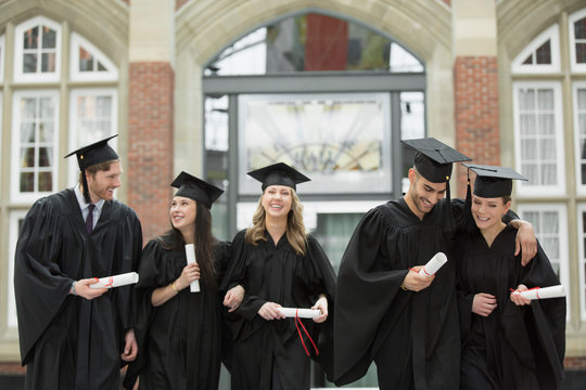 College graduates walking with diplomas