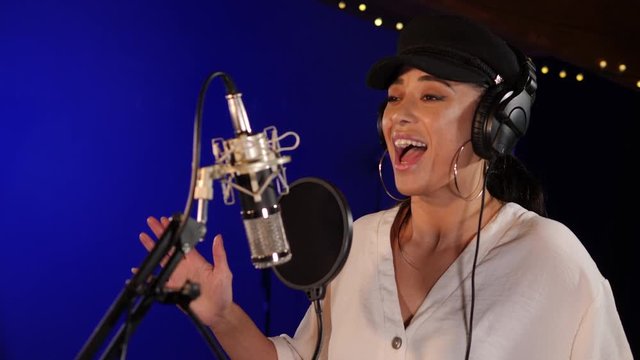 Female Singer / Popstar recording an Album in the studio - She sings into the Microphone wearing headphones