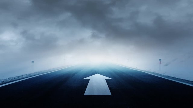 Straight arrow sign painted on asphalt road with dark mystic cloudy sky.