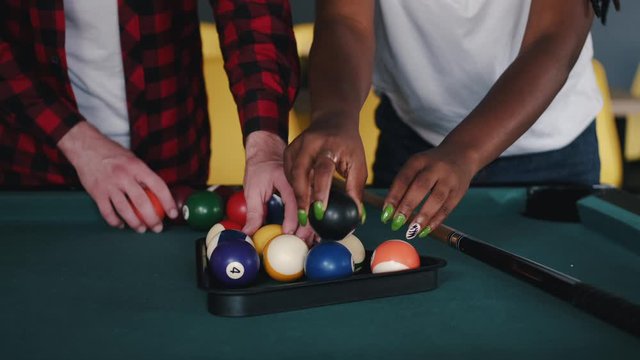 The billiard balls are colorful. The table is green. People play billiard.