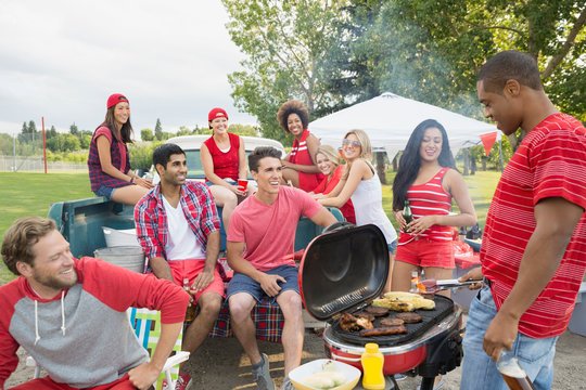 Friends relaxing at tailgate barbecue in field