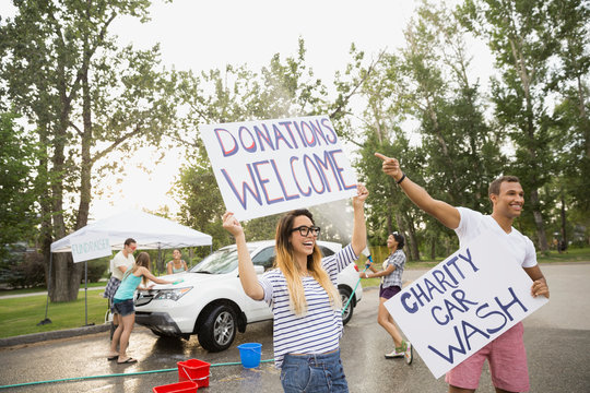 Enthusiastic volunteers waving charity car wash signs