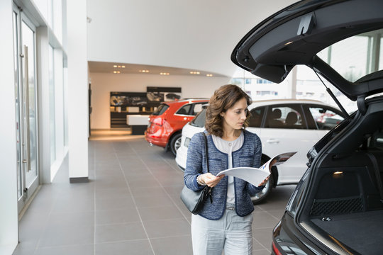 Woman with brochure in car dealership showroom