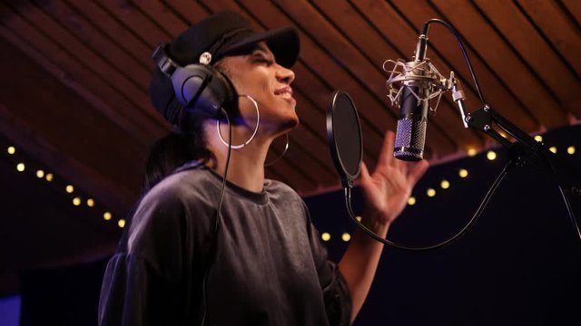 Female Singer / Popstar recording an Album in the studio - She sings into the Microphone. Vocalist singing a song. Pan up