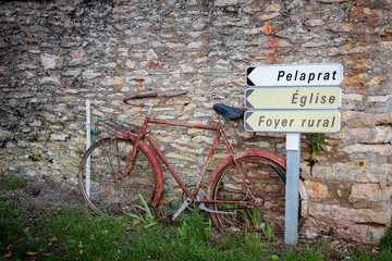 Vieux vélo abandonné sur le muret du village