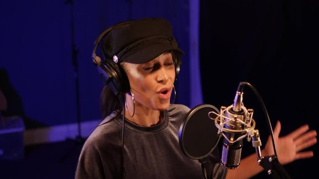 Female Singer / Popstar recording an Album in the studio - She sings into the Microphone with headphones on
