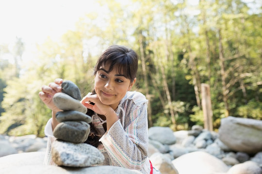 Young woman stacking stones in woods