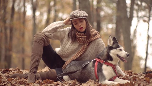 Young girl with a dog husky in uatumn park outdoors. Concept friendship with dog. Autumn girl plays with a dog (husky).