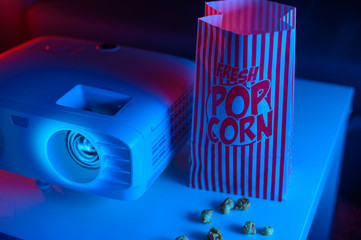 Projector for watching movies for home, or a movie theater with popcorn on a dark background