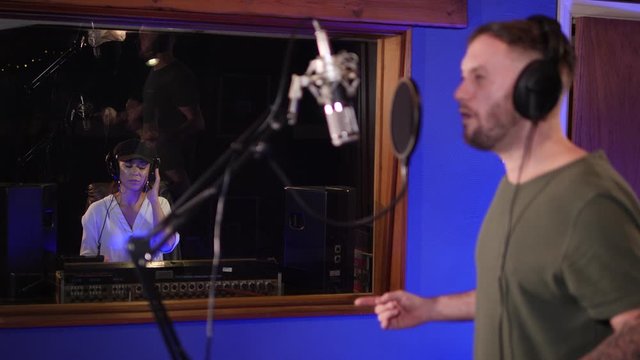 Male Singer / Popstar recording an Album in the studio - With female Sound Engineer behind mixing the track