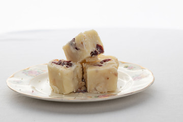 Pieces of sweet white fudge on a plate on a white background