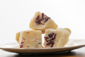 Close up of Pieces of white fudge with cranberries on a white background