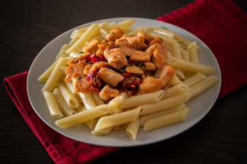 Penne pasta with chicken and vegetables in tomato sauce