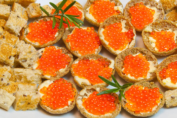 Sandwiches with red caviar on white plate close up