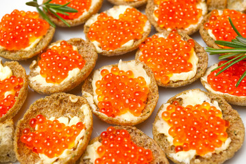 Sandwiches with red caviar on white plate close up