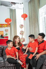Asian family with two son holding ang pao chatting together.Asian Chinese family celebrates Lunar New Year