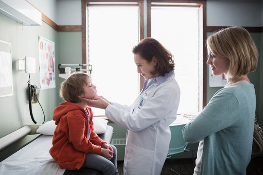 Pediatrician checking glands of boy in examination room