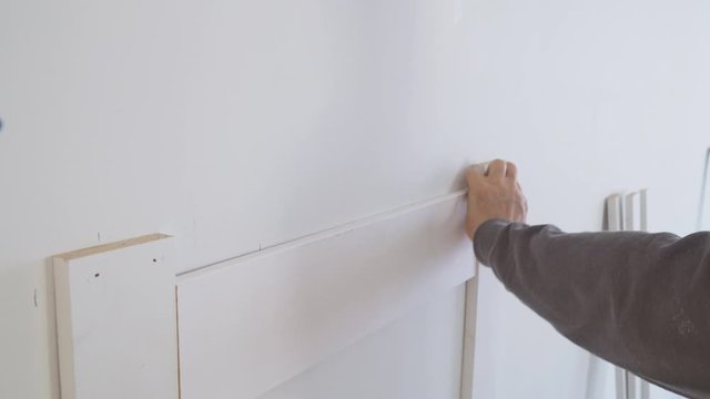 arpenter using nail gun nstallation mouldings on the wall of fragment of molding,