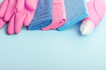Cleaning products, gloves and rags on blue background with copy space