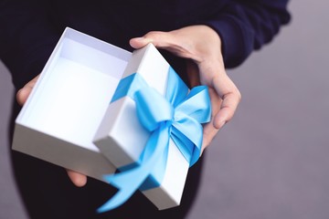 Blue bow gift box in woman's hand for lover on birthday, new year, valentines day