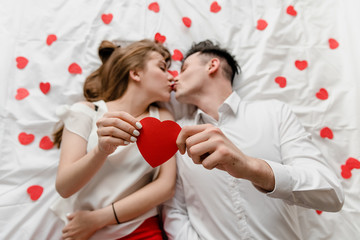 man and woman in love in bed with heart shapes