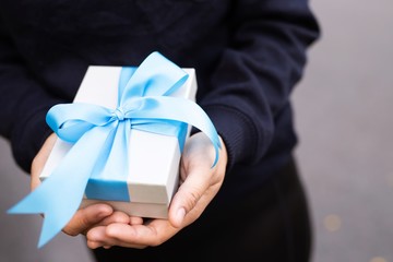 Blue bow gift box in woman's hand for lover on birthday, new year, valentines day