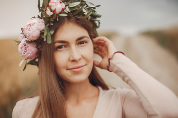 Naklejka premium Beautiful girl in a brown dress. Woman in a summer field in a wreath