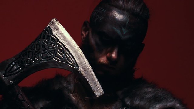 Portrait of a possessed Viking slowly raising his head, thoughtlessly looking at the camera. A bearded warrior in armor, aggressively looking at the camera, with a red background in the smoke