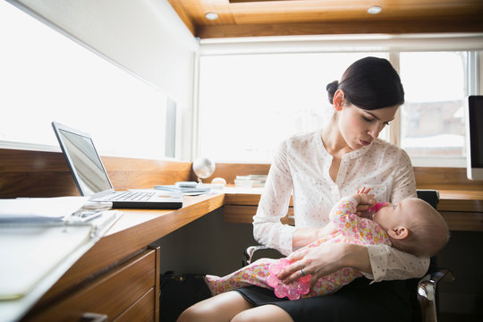 Mother holding baby in home office