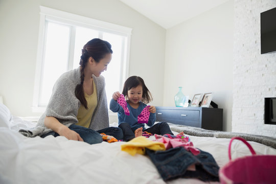 Mother and daughter sorting laundry on bed