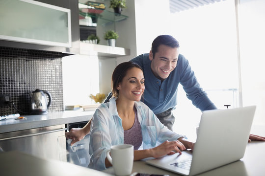 Smiling couple at laptop in kitchen