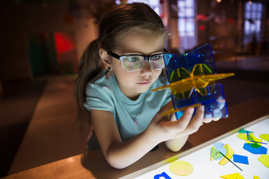 Curious girl holding geometric shape in science center