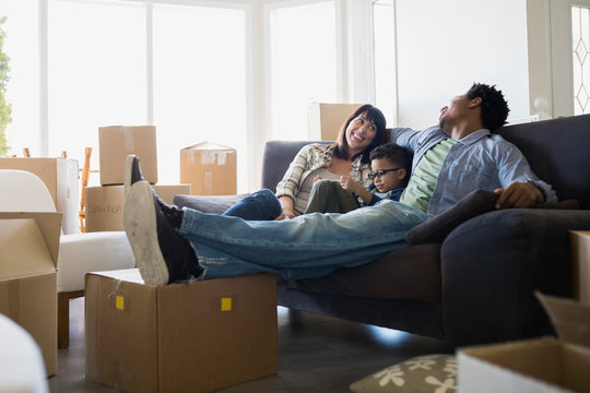 Moving boxes surrounding family relaxing on sofa