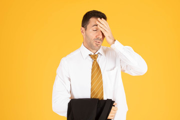 Portrait of businessman feeling stressed and tiring on yellow background.