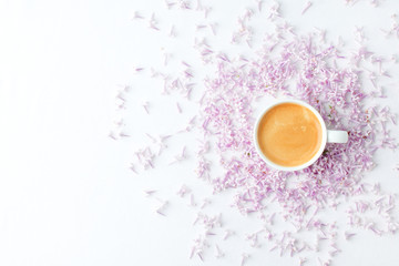 Morning breakfast with coffee cup and lilac flowers on white background. Flat lay, top view women background. Minimal concept, wedding, valentine day, copy space