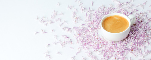 Morning breakfast with coffee cup and lilac flowers on white background. Flat lay, top view women background. Minimal concept, wedding, valentine day, copy space, banner
