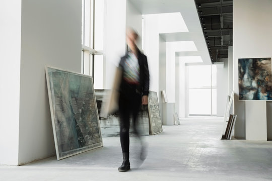 Art dealer walking with paintings in art gallery