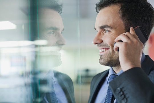 Smiling businessman using mobile phone in office