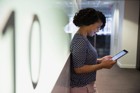 Businesswoman using digital tablet in office corridor